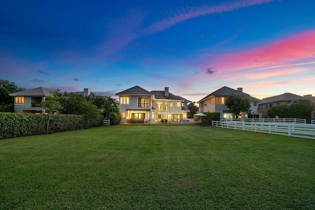 back house at dusk featuring a yard