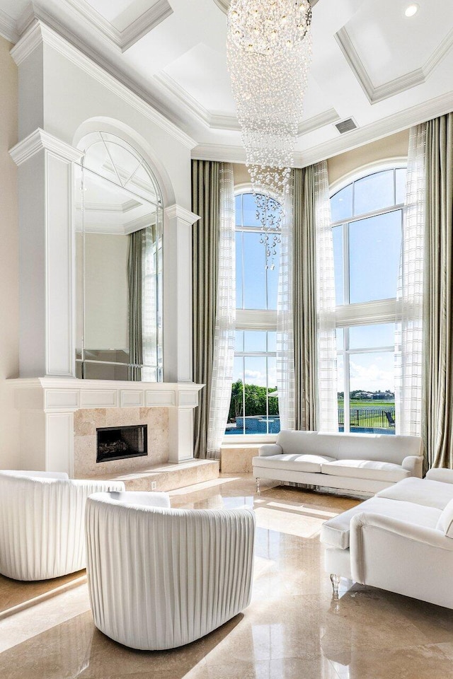 sitting room featuring a high end fireplace, ornamental molding, coffered ceiling, and an inviting chandelier