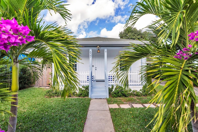 view of exterior entry with a porch and a lawn