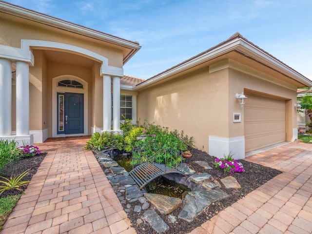 property entrance with an attached garage and stucco siding