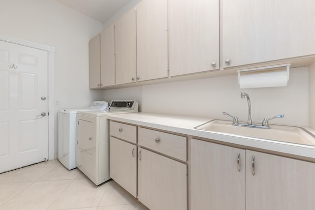 laundry room with washer and clothes dryer, light tile patterned flooring, cabinets, and sink