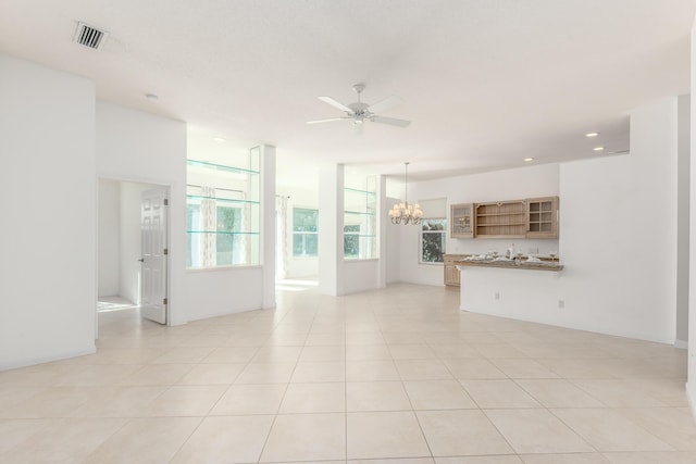 unfurnished living room featuring light tile patterned floors and ceiling fan with notable chandelier