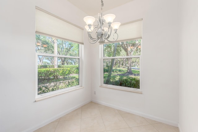 tiled spare room with a notable chandelier