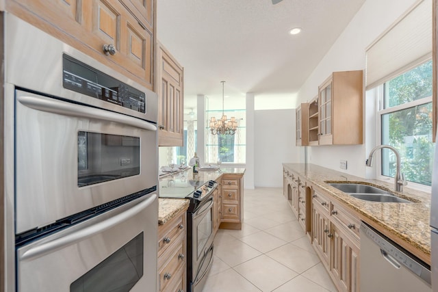 kitchen with light stone countertops, appliances with stainless steel finishes, sink, pendant lighting, and an inviting chandelier