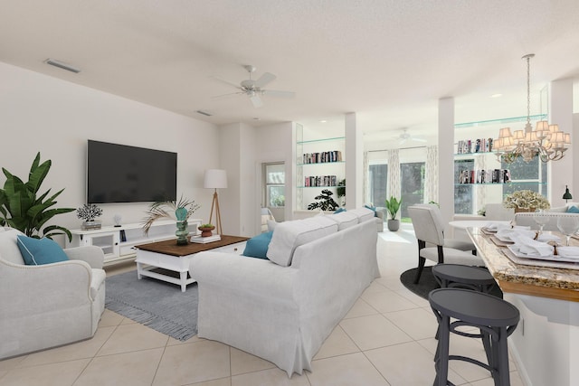 tiled living room featuring ceiling fan with notable chandelier