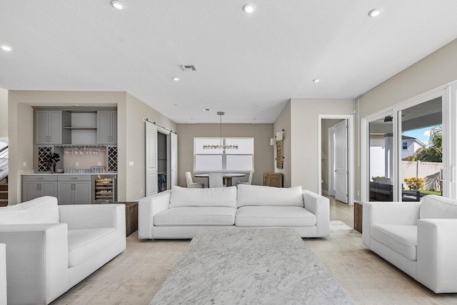 living room featuring a textured ceiling, indoor bar, beverage cooler, and a healthy amount of sunlight