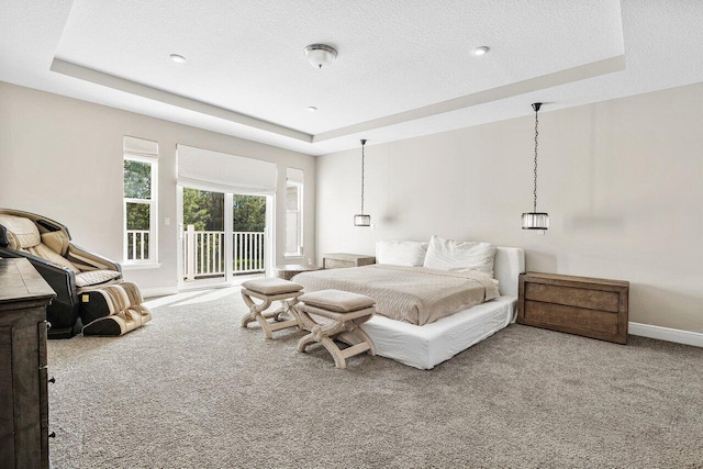 carpeted bedroom with a raised ceiling, access to exterior, and a textured ceiling