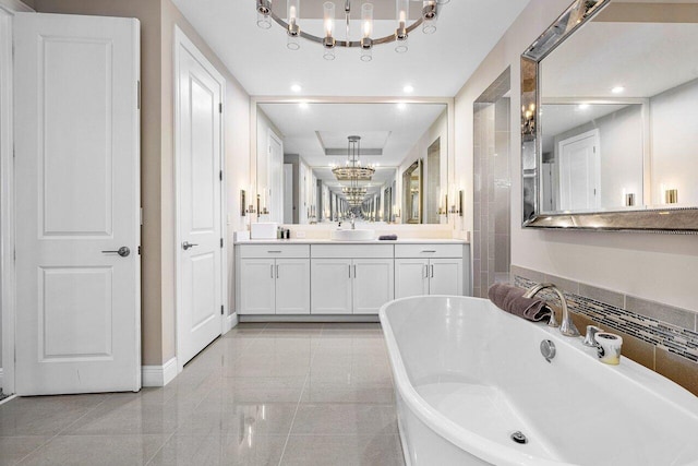 bathroom with a tub to relax in, vanity, and an inviting chandelier