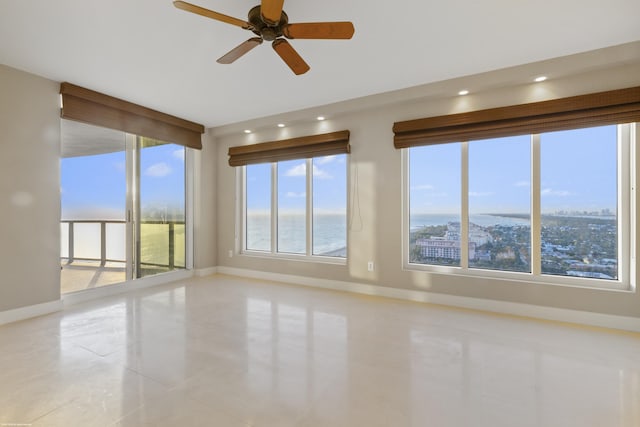 tiled spare room with ceiling fan, a healthy amount of sunlight, and a water view