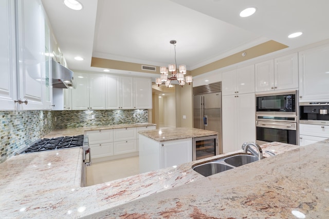 kitchen with ventilation hood, sink, built in appliances, white cabinets, and hanging light fixtures