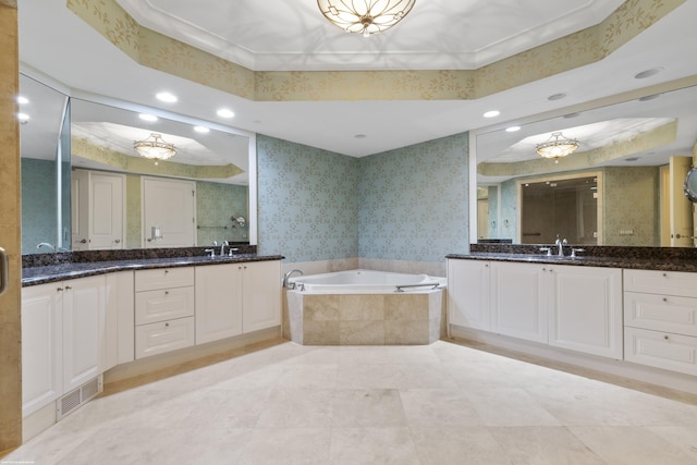 bathroom featuring a raised ceiling, vanity, a relaxing tiled tub, and ornamental molding