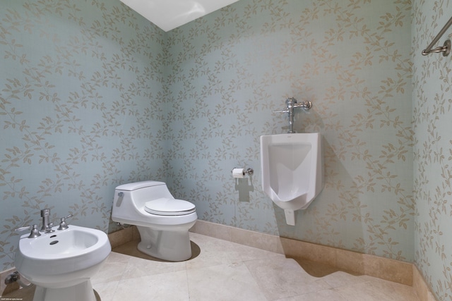 bathroom with toilet, tile patterned floors, and a bidet