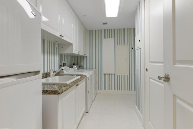 washroom with cabinets, washer and clothes dryer, and sink