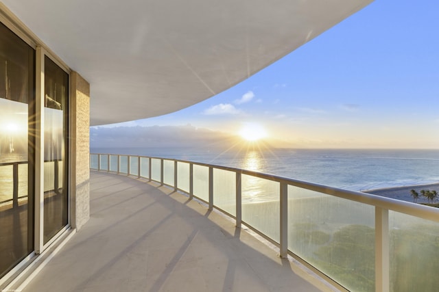 balcony at dusk with a water view and a beach view