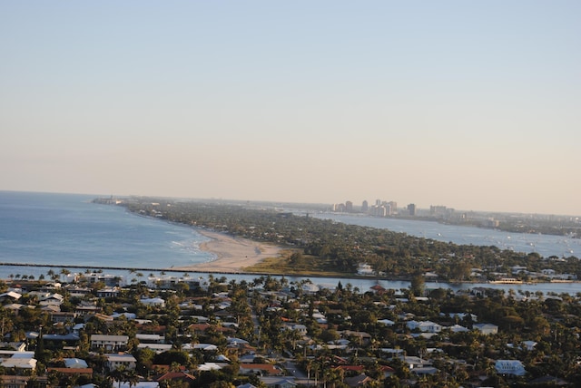 aerial view at dusk featuring a water view and a view of the beach