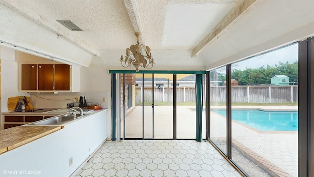 kitchen with sink, vaulted ceiling with beams, and a chandelier