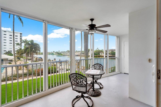 sunroom / solarium with ceiling fan and a water view