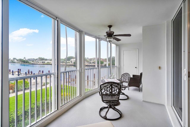 sunroom / solarium with ceiling fan, plenty of natural light, and a water view