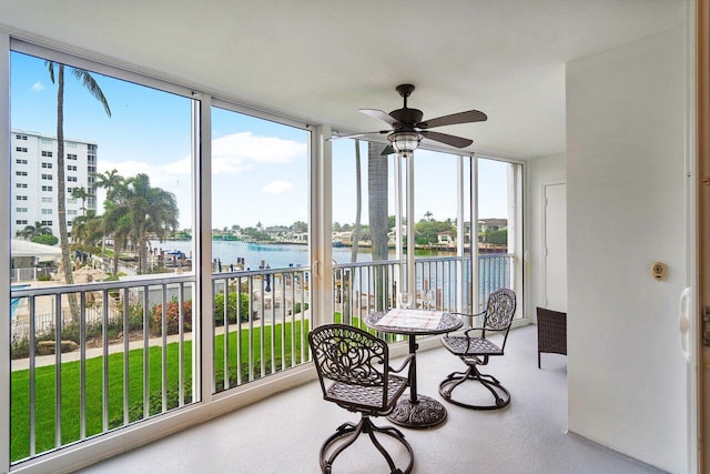 sunroom / solarium with ceiling fan, a water view, and a healthy amount of sunlight