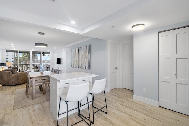 kitchen featuring a center island, hanging light fixtures, light hardwood / wood-style flooring, a breakfast bar, and white cabinets