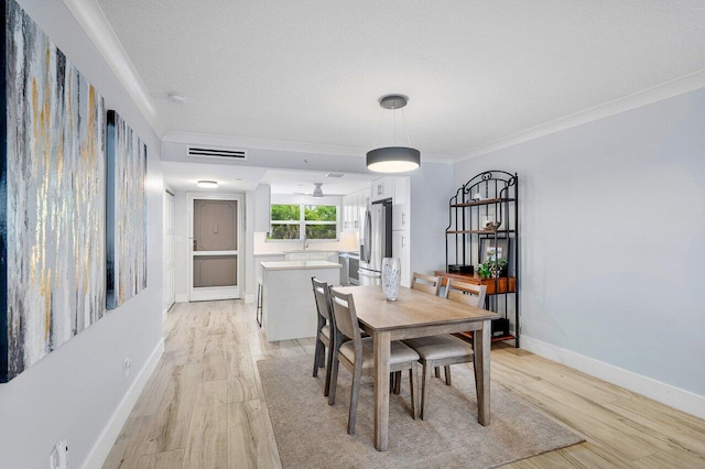 dining space featuring a textured ceiling, crown molding, and light hardwood / wood-style flooring