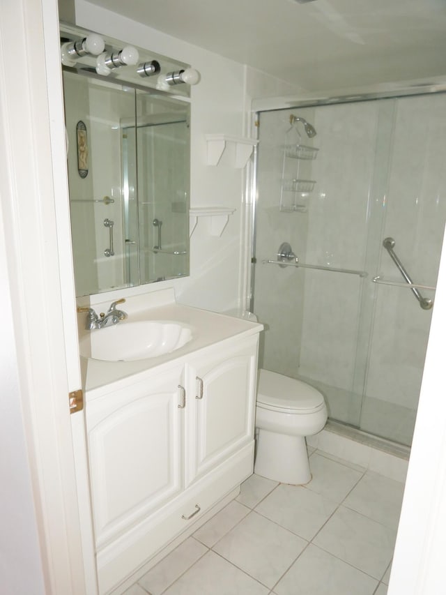 bathroom featuring tile patterned flooring, vanity, toilet, and a shower with door