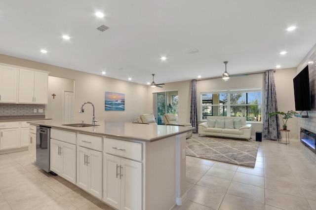 kitchen with backsplash, a kitchen island with sink, white cabinets, sink, and stainless steel dishwasher