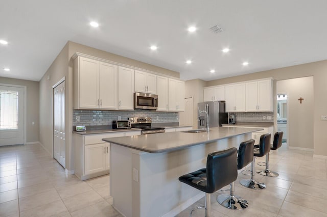 kitchen with white cabinetry, a center island with sink, and stainless steel appliances