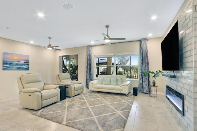 living room with ceiling fan, a large fireplace, and light tile patterned flooring