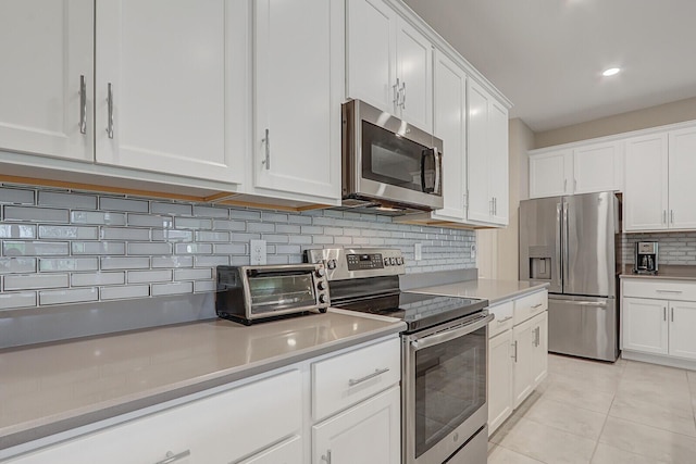 kitchen featuring light tile patterned floors, white cabinetry, appliances with stainless steel finishes, and tasteful backsplash