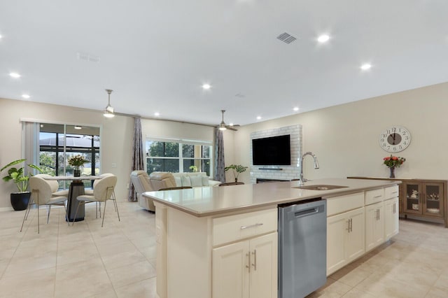 kitchen with stainless steel dishwasher, ceiling fan, sink, white cabinetry, and an island with sink