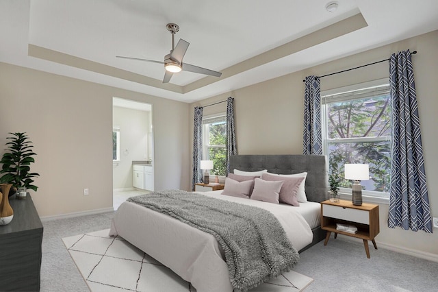 bedroom featuring a tray ceiling, ceiling fan, and ensuite bathroom