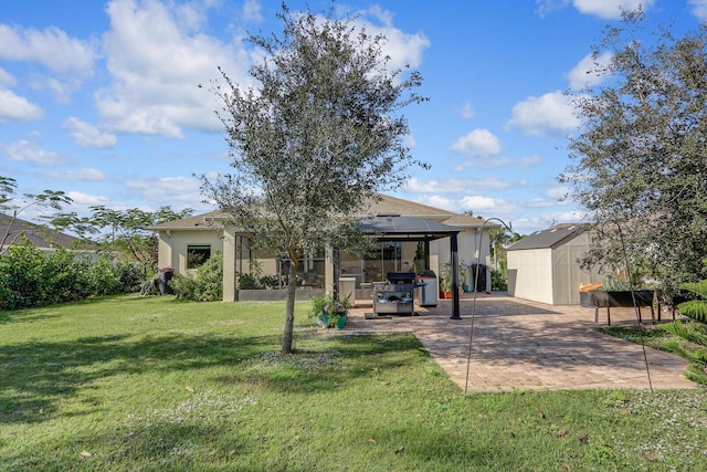 rear view of property with a gazebo, a yard, a shed, and a patio area