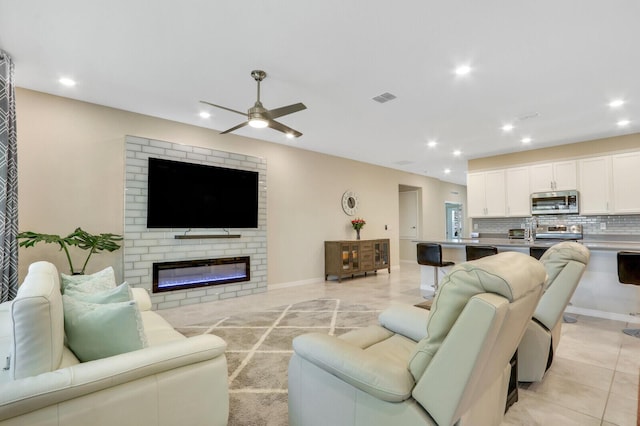 living room featuring ceiling fan and a brick fireplace