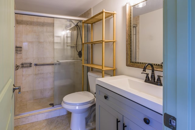 bathroom featuring tile patterned floors, toilet, a shower with shower door, and vanity