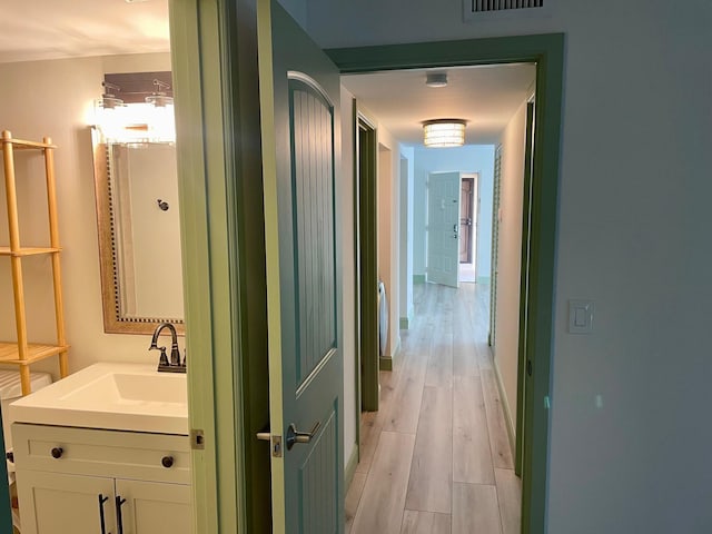 corridor featuring sink and light wood-type flooring