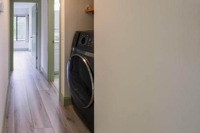 clothes washing area featuring washer / clothes dryer and light hardwood / wood-style flooring