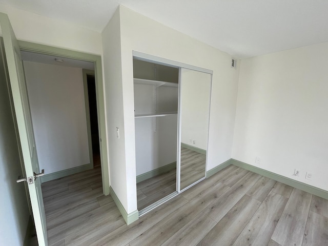 unfurnished bedroom with light wood-type flooring and a closet