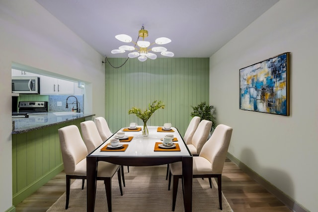 dining area featuring hardwood / wood-style flooring, sink, and a notable chandelier