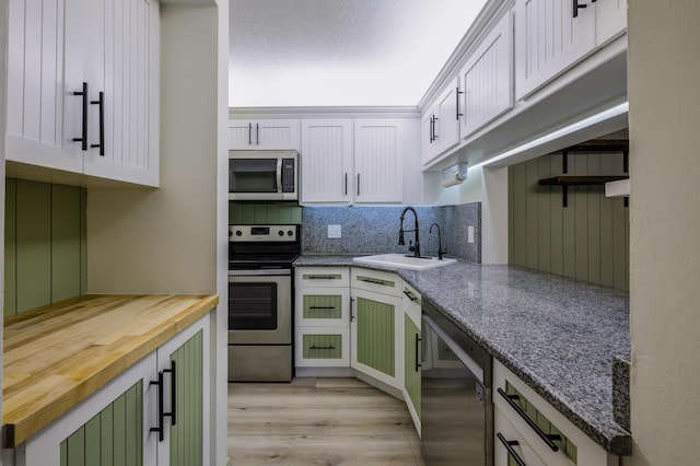 kitchen with white cabinetry, light stone counters, and appliances with stainless steel finishes