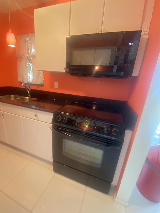 kitchen with light tile patterned flooring, sink, white cabinetry, and black appliances