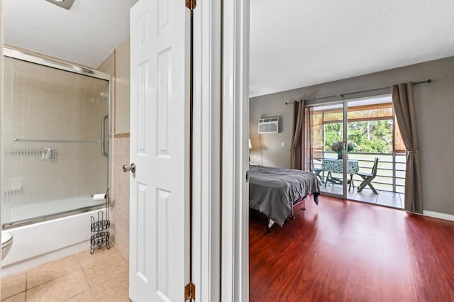 bedroom with a wall mounted AC, wood finished floors, and access to exterior