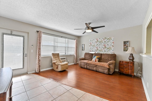 living room with a ceiling fan, a textured ceiling, baseboards, and wood finished floors