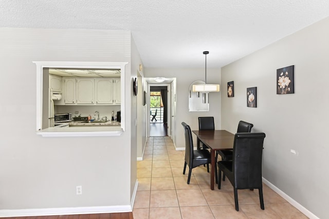 dining space with baseboards, a textured ceiling, and light tile patterned flooring