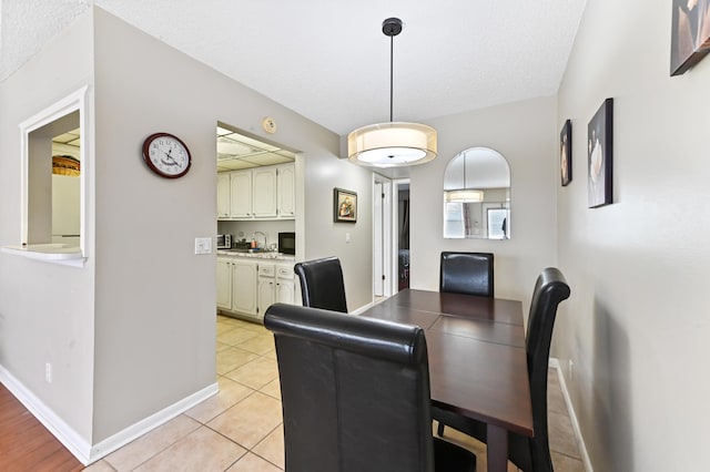 dining area featuring baseboards, a textured ceiling, and light tile patterned flooring