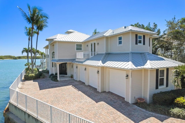 view of front of house featuring a garage, a balcony, and a water view