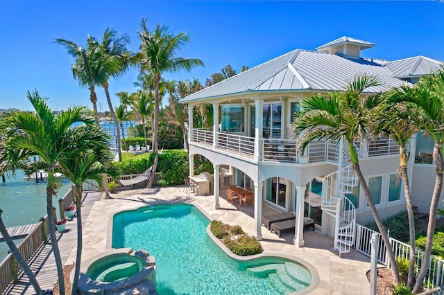 rear view of property with a patio and a pool with hot tub