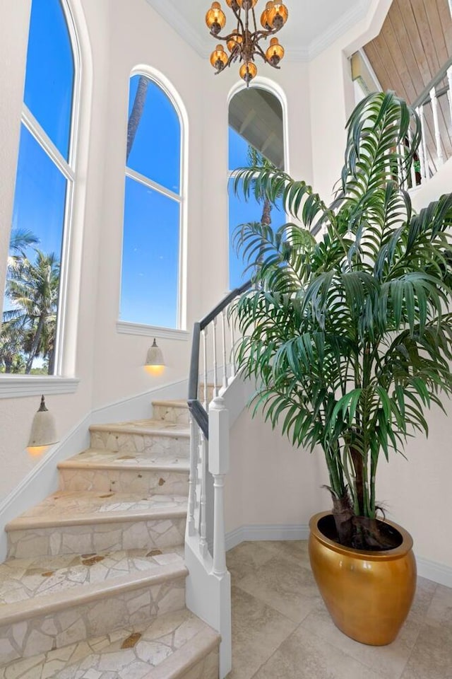 staircase featuring ornamental molding and a notable chandelier