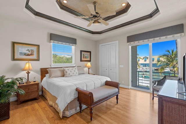 bedroom featuring access to outside, ceiling fan, ornamental molding, a tray ceiling, and a closet