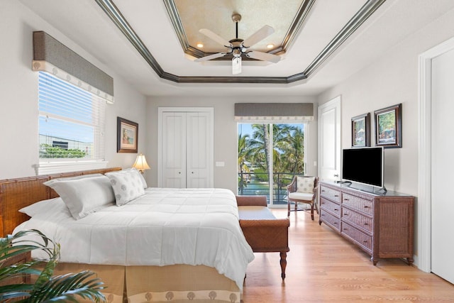 bedroom with light wood-type flooring, access to outside, a raised ceiling, ceiling fan, and crown molding